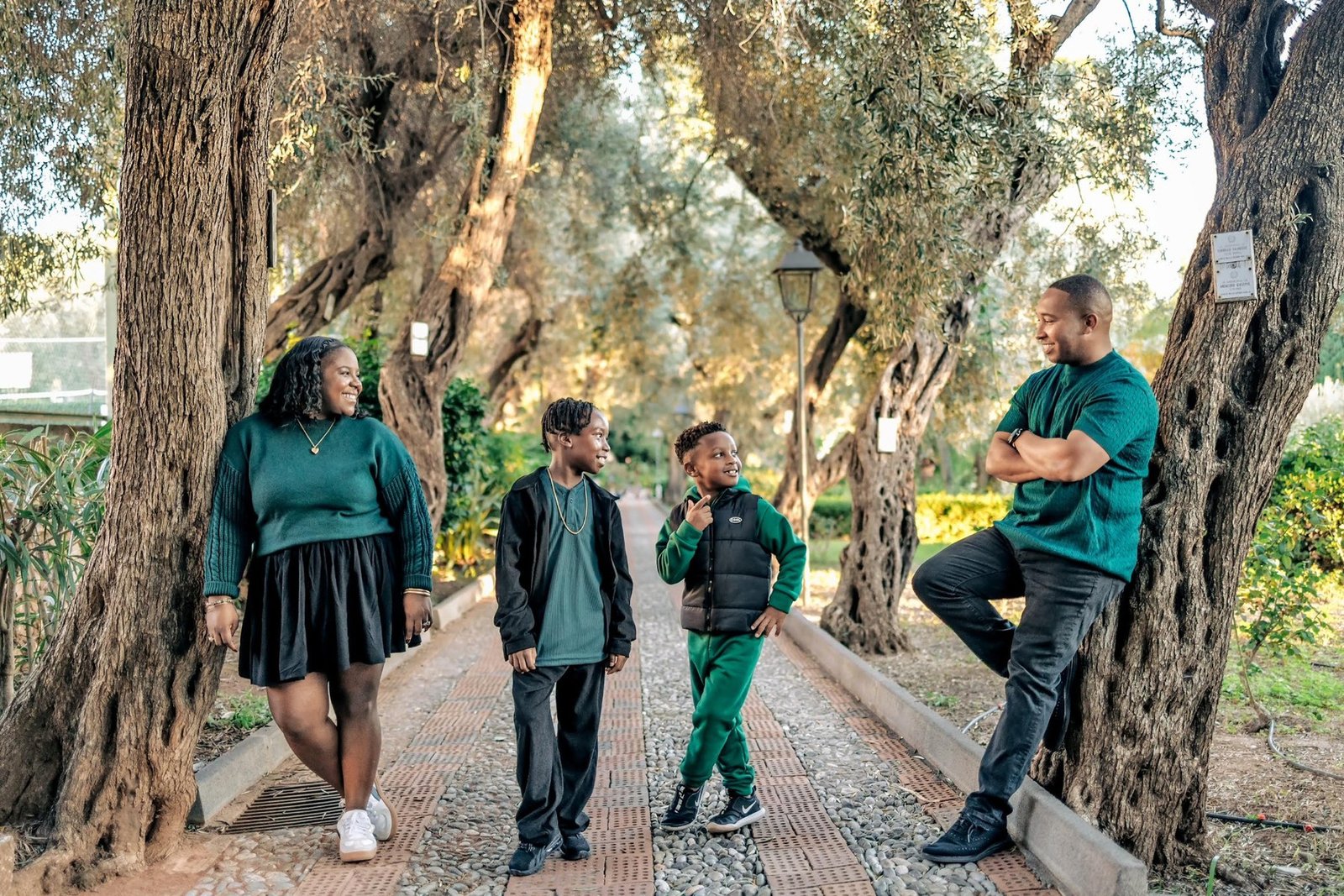 A family of four walking together beneath trees
